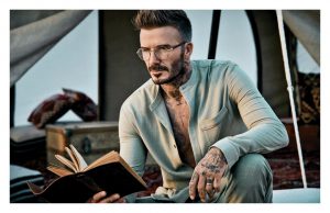 David Beckham models golden glasses as he poses in retro snaps for his new eyewear range