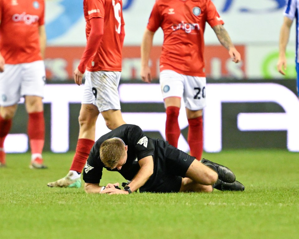 EFL clash delayed for 20 MINUTES after referee injures head in horror collision… as fan takes over as fourth official