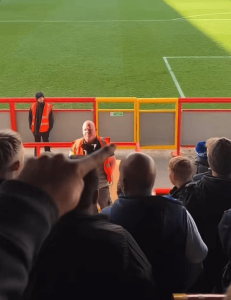 Brilliant moment steward who’s the spitting image of darts legend is serenaded by football fans